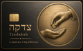 Black metal credit card with embossed hands passing a coin inside a circular frame, Hebrew lettering, and the tagline A small act. A big difference.
