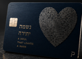 Navy metal credit card with a large fingerprint pattern of concentric lines forming a heart shape and Hebrew lettering