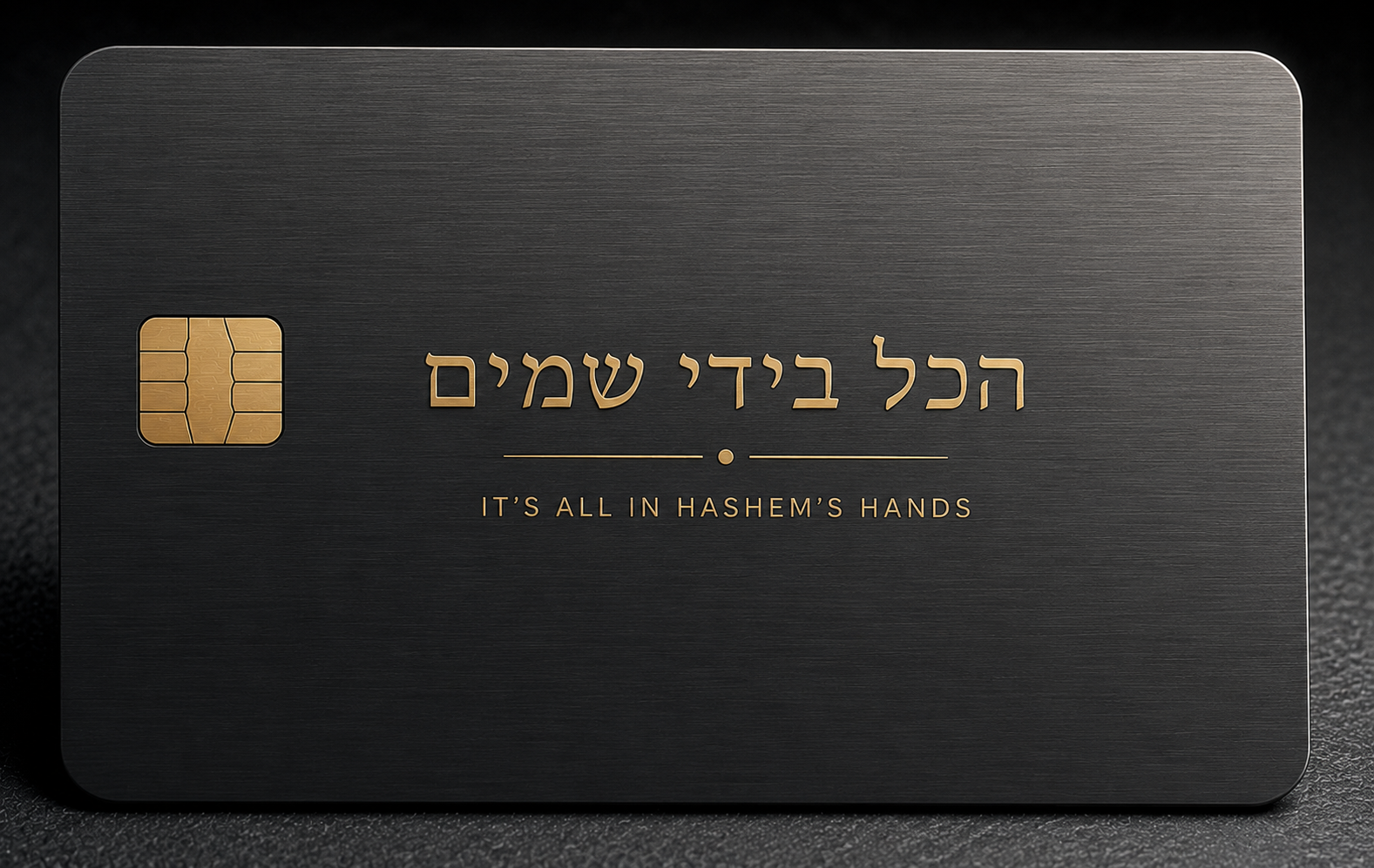 Dark grey metal credit card with Hebrew lettering arranged as a large central pattern and an English tagline beneath